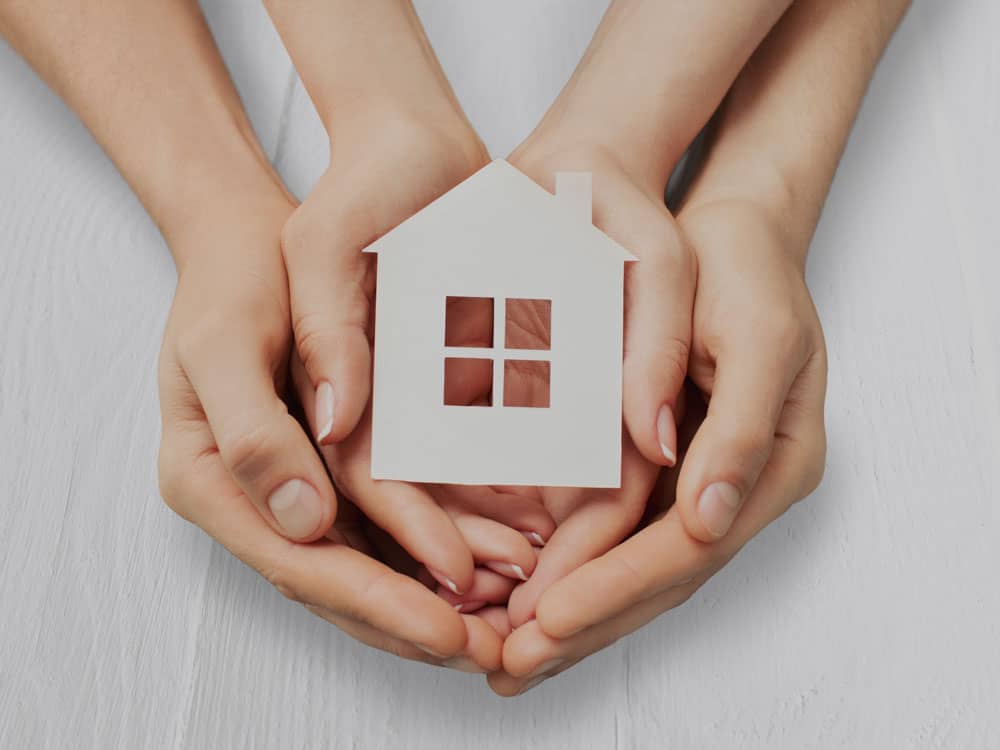 Hands holding house paper shape